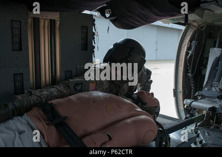 Sgt. Carlton Quenneville, Crew Chief, Charlie Company, 3.BATAILLON, 126 Aviation Regiment (Air Ambulance), unbuckles eine Unfallversicherung für Drop-off bei der Verteidigung und Unterstützung der zivilen Behörden bei der Army Aviation Support Facility, South Burlington, VT April 2, 2016. Die Ausbildung ist die Vorbereitung für die Wachsam Guard, National Emergency Response Übung. (U.S. Army National Guard Foto von SPC. Avery Cunningham) Stockfoto