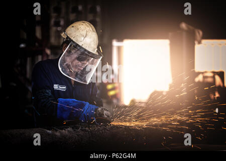 Elektrische rad Schleifen auf Stahlkonstruktion im Werk. Handyman mit elektrischer Grinder, schleifen Stahlkonstruktion, Fokus auf Tools, Low Light Stockfoto