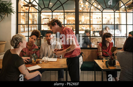 Kellner, die Aufträge von Kunden in einem Bistro sitzen Stockfoto