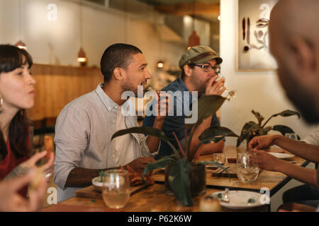 Lächelnden jungen Freunde genießen Sie ein gemeinsames Abendessen in einem trendigen Bistro Stockfoto
