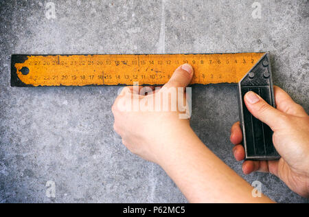 Person mit setsquare auf graue Wand. Close-up. Stockfoto