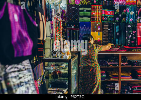 Yangon, Myanmar - Feb 19 2014: Frauen in einem Tuch Geschäfte Stall der Bogyoke Aung San Market Stockfoto