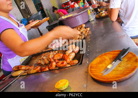 Einheimische Frau kochen Fleisch für Asado bei Mercado 4 in Asuncion, Paraguay. Asado ist ein traditionelles Gericht in Paraguay und in der Regel besteht aus Rindfleisch neben Stockfoto