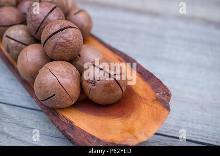 Geröstete und gesalzene Macadamianüsse auf rustikalen Holzmöbeln Hintergrund. Platz kopieren Stockfoto