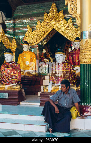 Yangon, Myanmar - Feb 19 2014: Burma männlich Sitzen vor Tempel in der Shwedagon Pagode Stockfoto