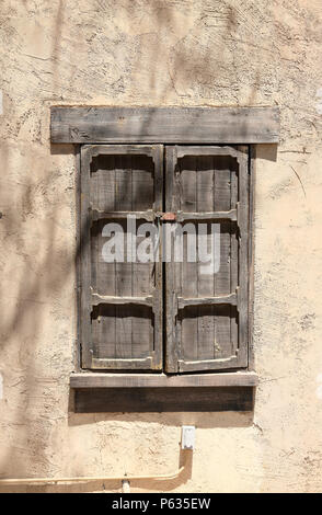 Altes Holz gerahmte Fenster mit Fensterläden mit einem Schloss, in einem Adobe Wand Stockfoto