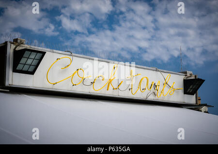 Beleuchtetes Zeichen mit schriftlicher Cocktails mit gelben Farben auf einem blauen Himmel und viele Wolken mit viel Freiraum. Nützlich für die Werbung von Res Stockfoto