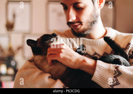 Junger Mann mit seinem Haustier siamesische Katze Stockfoto