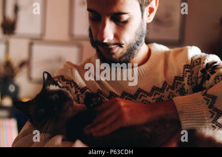 Junger Mann mit seinem Haustier siamesische Katze Stockfoto