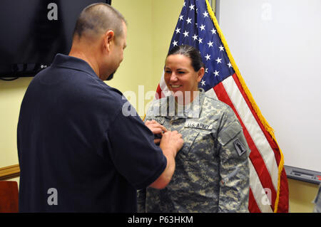 David Coles pins Staff Sgt. Heather Simmons, ein Eingeborener von Jacksonville, Florida zu der US-Armee finden 99. Regionale Unterstützung Befehl an Joint Base McGuire Dix-Lakehurst, New Jersey zugeordnet, mit dem Rang eines Warrant Officer Candidate April 29. Stockfoto