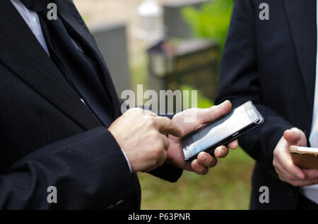 Älterer Mann im dunklen Anzug mit einem Mobiltelefon Stockfoto