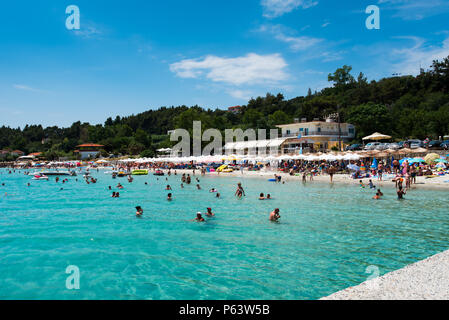 Chaniotis, Griechenland - 23. Juni 2018: Popullar Chaniotis Stadt Strand in Kassandra, Chalkidiki mit vielen Touristen genießen den sonnigen Tag Stockfoto