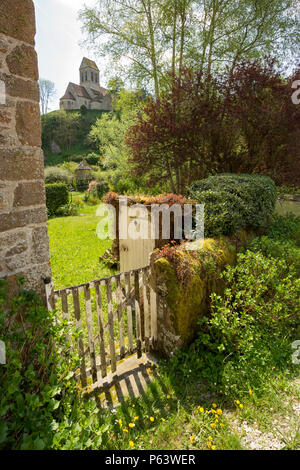 Saint-Ceneri-le-Gerei, Normandie Frankreich: Tor zu einem Garten mit der alten Kirche im Hintergrund. Stockfoto