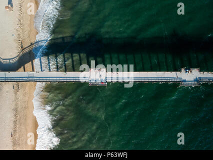 Eine Luftaufnahme bei 330 Fuß/100 m auf einem südlichen Kalifornien Pier auf einer kleinen Halbinsel. Weißer Schaum von Wellen und Vibr Stockfoto