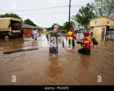 Texas Wachposten und Texas Task Force 1 Rettungskräfte durch Oberschenkel Wade - tiefes Wasser gestrandeten Bewohner zurück zur Rettung von Fahrzeugen, die während der schweren Überschwemmungen in Wharton, Texas, 21. April 2016 zu helfen. In Abstimmung mit Texas Task Force 1 und die Stadt von Wharton Notdienste, eine Loslösung von Delta Unternehmen der Annahme Brigade Support Battalion, Texas Army National Guard mehrere leichte Multi-Gelände Fahrzeuge das Hochwasser die Rettung von Menschen und Haustiere eingesetzt. (U.S. Army National Guard Foto von 1 Lt Zachary West) Stockfoto