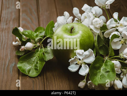 Green Apple mit Blüten auf hölzernen Tisch Stockfoto