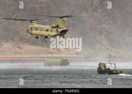 Fort Drum, New York-based Soldaten der 6. Staffel, den 6 Reiterregiment ix-Shooters, '10 Combat Aviation Brigade, in einer CH-47 Chinook, Luftbrücke ein Segment eines schwimmenden Brücke zu den Imjin River April 6, als Soldaten der 74th Multi-Role Brücke Unternehmen "RiverRats' 62 Engineer Battalion, 36th Engineer Brigade bewegen in das Segment zu erfassen und sie in die richtige Position verschieben Sie eine schwimmende Brücke zu erstellen. Us-amerikanischen und südkoreanischen Truppen führte eine 4-tägige, kombinierte Waffen River Crossing Ausübung von April 5-8, eines der größten seiner Art in mehr als einem Jahrzehnt. (U.S. Armee Foto: Staff Sgt Stockfoto