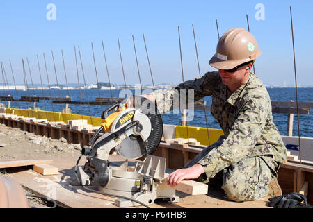 160425-N-HU 290-044 Yokosuka, Japan (Apr. 25, 2016) - Constructionman Duston Wright, zugeordnet zu den Naval Mobile Konstruktion Bataillon (NMCB) 4, schneidet ein Stück Holz mit einer Kreissäge die Schalung entlang der Bucht von Tokio in Yokosuka, Japan. NMCB 4 ist der Vorwärts bereitgestellt Pacific NMCB bereit, größeren Kampfhandlungen zu unterstützen, humanitäre Hilfe/Disaster relief Operations und General Engineering Support zum Navy, Marine Corps und gemeinsamer operativer Kräfte zur Verfügung stellen. (U.S. Marine Foto von Bau Elektriker 3. Klasse Christopher Evenson/Freigegeben) Stockfoto