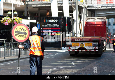 Einen marshall Verkehr anhalten, damit ein Lkw aus einer Baustelle, London Bridge, Großbritannien in den Rückwärtsgang Stockfoto