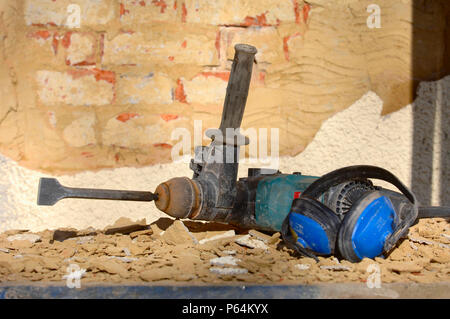 Ein Leistungsschalter Maschine verwendet alten Rendering von einer roten Mauer auf einer Hütte unter Renovierung zu entfernen, Großbritannien Stockfoto