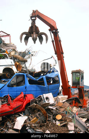 Mechanische Lader mit einem Enterhaken arm in einer Recyclinganlage am Anlegesteg in einem Hafen Newport, South Wales, Großbritannien Stockfoto