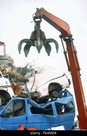 Mechanische Lader mit einem Enterhaken arm in einer Recyclinganlage am Anlegesteg in einem Hafen Newport, South Wales, Großbritannien Stockfoto