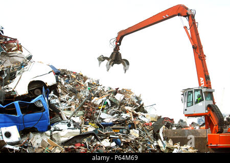 Mechanische Lader mit einem Enterhaken arm in einer Recyclinganlage am Anlegesteg in einem Hafen Newport, South Wales, Großbritannien Stockfoto