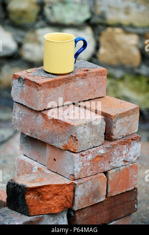 Ein Baumeister Becher Tee auf einem Stapel von aufgearbeiteten roten Ziegeln UK Stockfoto