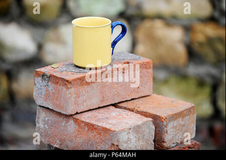 Ein Baumeister Becher Tee auf einem Stapel von aufgearbeiteten roten Ziegeln UK Stockfoto