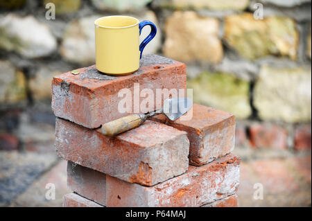 Ein Baumeister Becher Tee auf einem Stapel von aufgearbeiteten roten Ziegeln UK Stockfoto