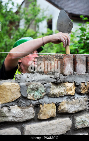 Bau einer Gartenmauer mit Cotswold Stone und aufgearbeiteten roten Ziegeln UK Stockfoto