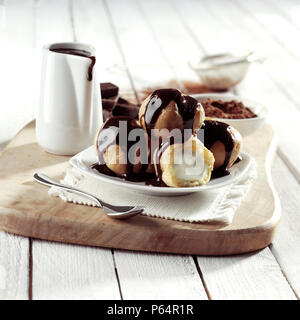 Windbeutel in Schokolade Soße Stockfoto