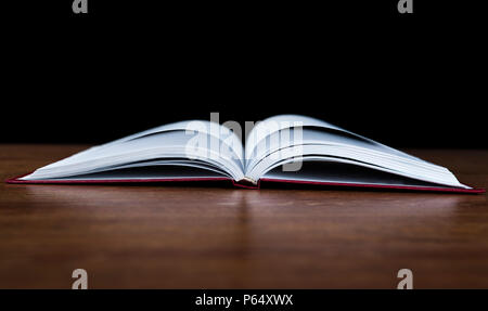 Offenes Buch auf dem Holz Tisch auf schwarzem Hintergrund Stockfoto