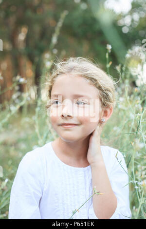 Porträt eines niedlichen kleinen Mädchen auf der Natur in den Blumen beim Gehen. Stockfoto