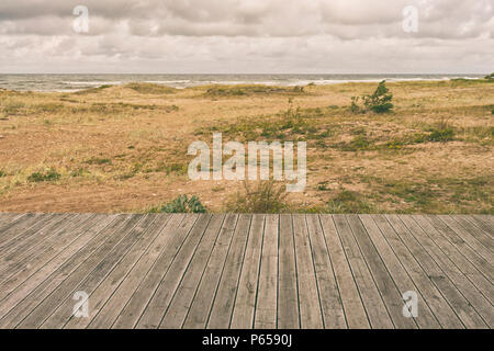 Gelbe Moos auf hölzernen Terrasse Geländer auf dem Sandstrand der Ostsee in einem Sturm Stockfoto