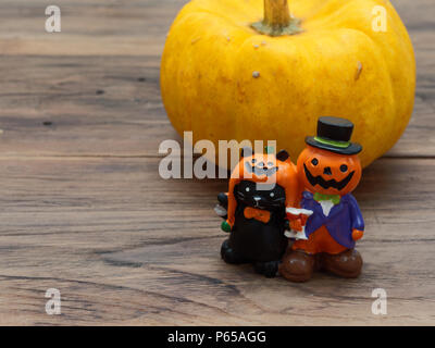 Nahaufnahme von gelb Bio Kürbis und orange Miniatur Keramik Kürbis Kerl mit schwarzen Katze auf dunklem Hintergrund in Halloween verwendet, Stillleben, Küche, und Vergleich, und Land Themen Stockfoto