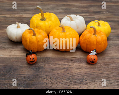 Orange miniatur Dekoration Keramik Kürbisse mit weißen Gespenst und schwarze Katze mit weißen, gelben und orangefarbenen Kürbisse auf dem Hintergrund über dunkle Holzfläche im Halloween verwendet und Dekoration Stockfoto