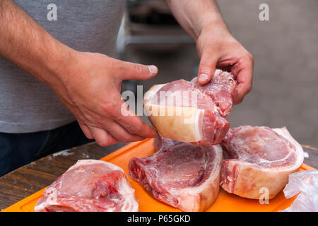 Nahaufnahme eines Kochs Mann breitet Sauce und Salz große Stücke von frischem Schweinefleisch entrecote für das Grillen. Der Mann ist Kochen Shish Kebab Stockfoto