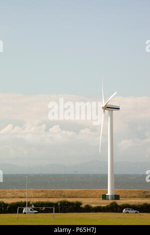 Eine onshore Wind Turbine am Stadtrand von Workington, Cumbria, Großbritannien. Im Hintergrund ist der neue "Robin Rigg Offshore Windpark im Solway Firth. R Stockfoto