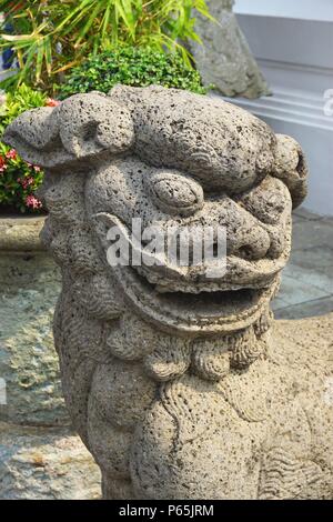 Nahaufnahme der lächelnden Statue des alten Steinlöwen im Königlichen Palast in Bangkok, Thailand. Das sagenhafte Tier dient als Wächter in der asiatischen Kultur. Stockfoto