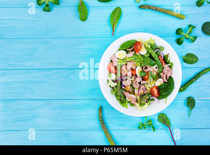 Salat mit Thunfisch, Tomaten, Wachteleier, Spargel und Zwiebeln auf Holz- Hintergrund Stockfoto