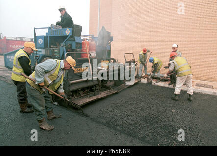 Straßenbau. Surfacing team Verbreitung beschichtet Splitt zu walzasphalt Deckschicht. Stockfoto