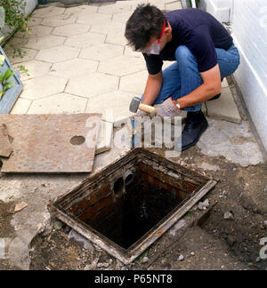 Installation eines Kanaldeckel über das Ablassen. Stockfoto