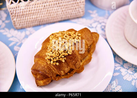 Heißes Croissant mit Muttern auf eine weisse Platte close-up. Stockfoto