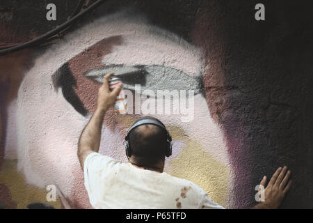 Junge Erwachsene Graffiti Künstler mit einem an der Wand arbeiten können. Leere Raum für Editor's Text. Stockfoto