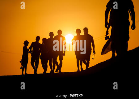 Eine Gruppe junger kolumbianischer Touristen zu Fuß auf die Steinmauern, die die koloniale Stadt, während des Sonnenuntergangs in Cartagena, Kolumbien. Stockfoto