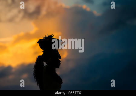 Eine afrokolumbianischen Mädchen, die als 'palenquera', trägt eine Schüssel voller Früchte auf dem Kopf während des Sonnenuntergangs in Cartagena, Kolumbien. Stockfoto