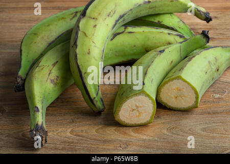 Ganze und halbe frische grüne unreife Bananen Stockfoto