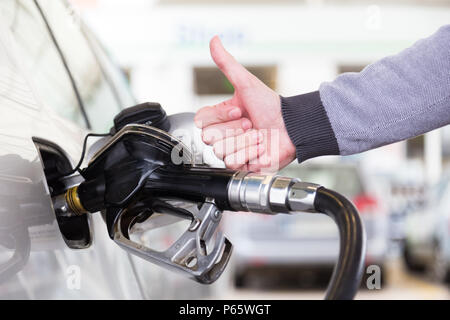 Benzin oder Benzin in einem Kraftfahrzeug Auto gepumpt. Nahaufnahme von mans hand, Daumen oben-Geste, Pumpen Benzin im Auto an der Tankstelle. Stockfoto