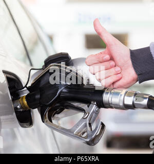 Benzin oder Benzin in einem Kraftfahrzeug Auto gepumpt. Nahaufnahme von mans hand, Daumen oben-Geste, Pumpen Benzin im Auto an der Tankstelle. Stockfoto
